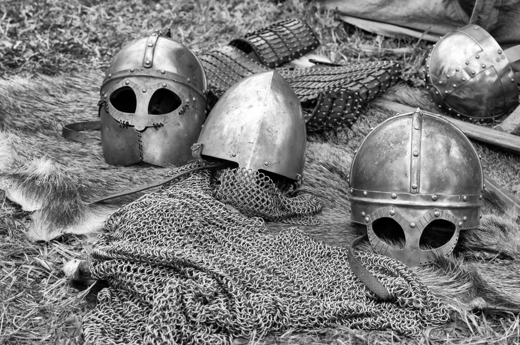 Close-up of historical medieval helmets and armor in black and white.